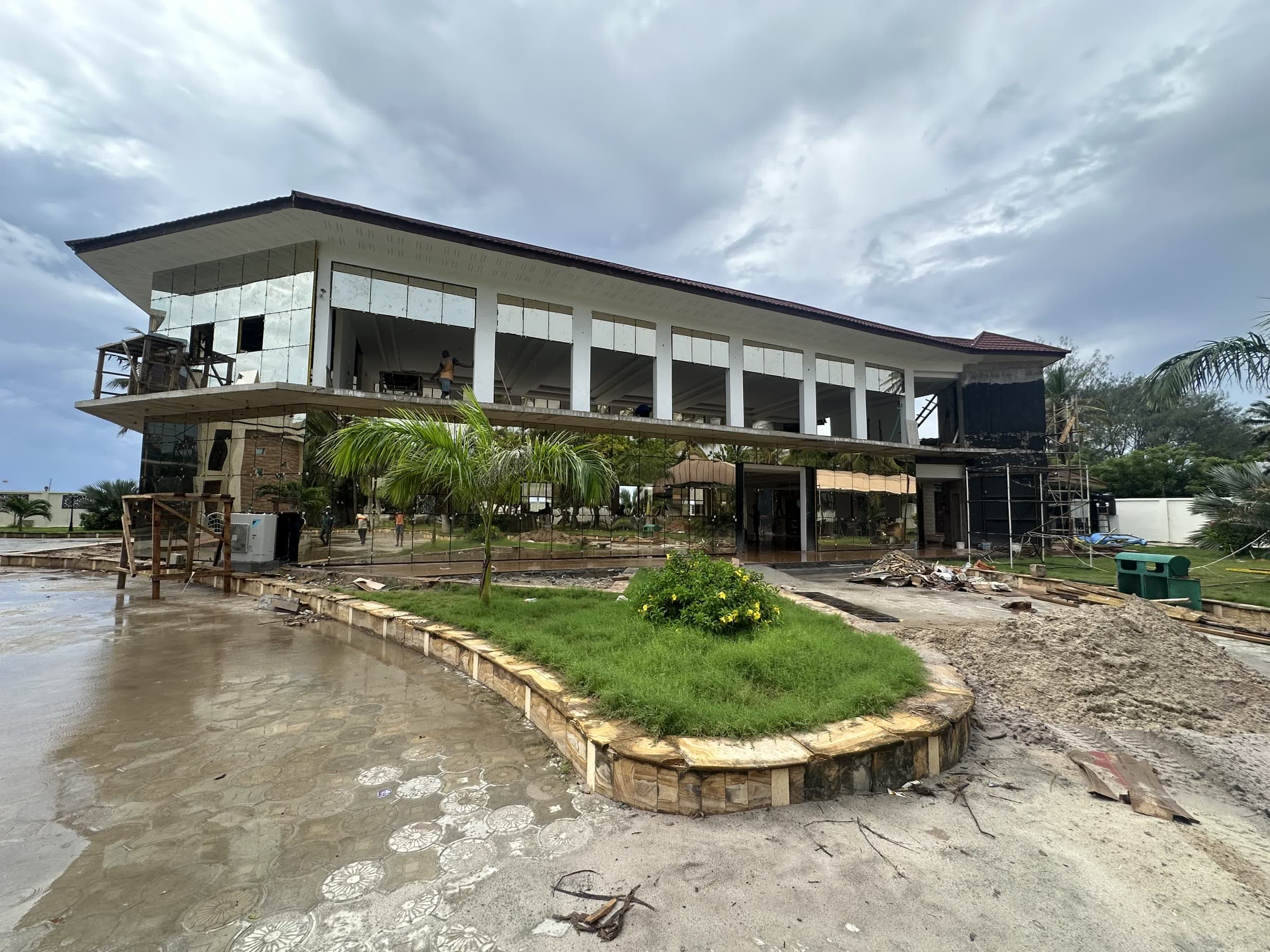 A boutique hospitality building reaching its finishing stage, with full-height glazing and a sweeping roofline
